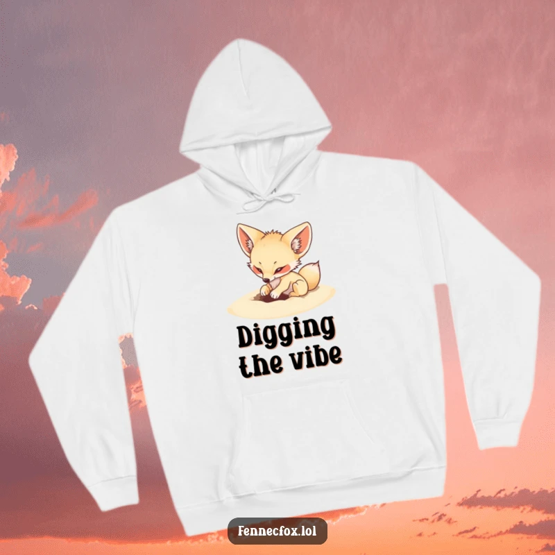 Funny hoodie showing a fennec fox playfully digging an energetic hole in soft sand, cozy desert vibes.