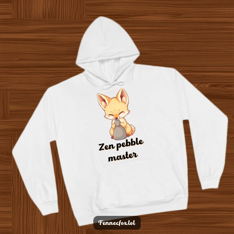Funny Fennec Fox Hoodie of a fennec fox concentrating hard to balance a pebble on its nose, offering warmth and amusement.